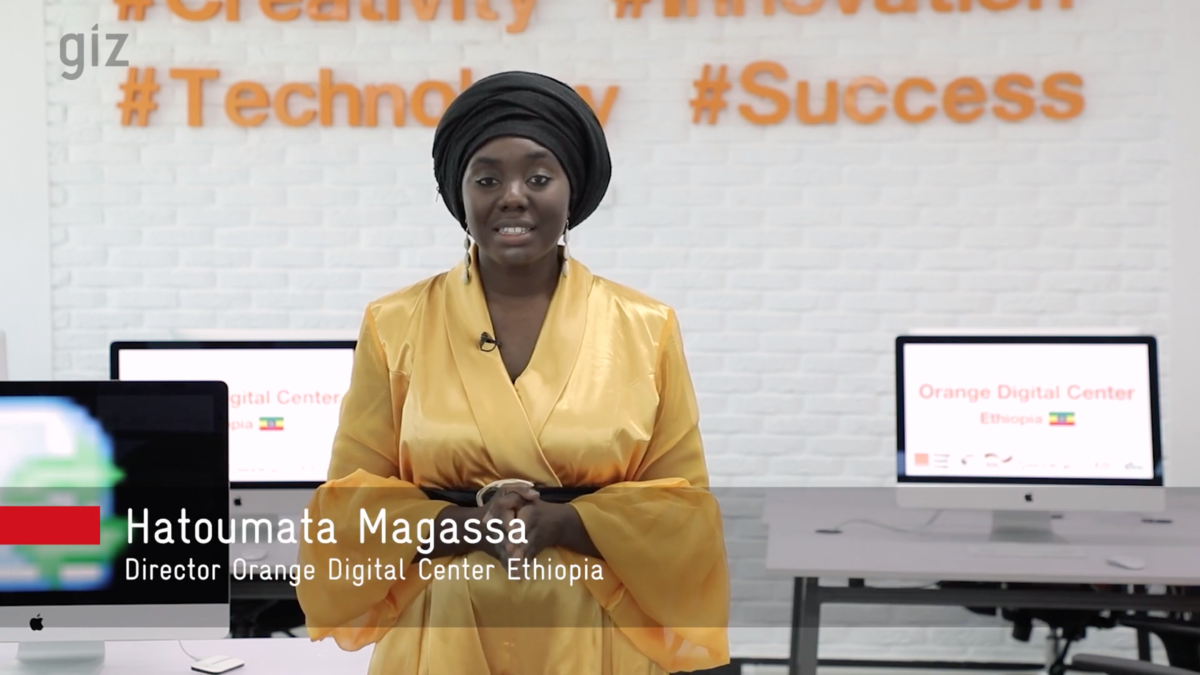 Photo: Hatoumata Magassa stands in front of desks, with computer monitors switched on.