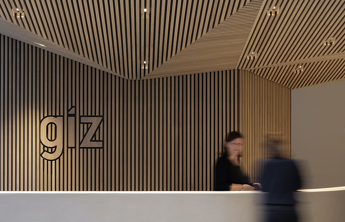 Photo: Reception desk inside a building with a GIZ logo on the wall
