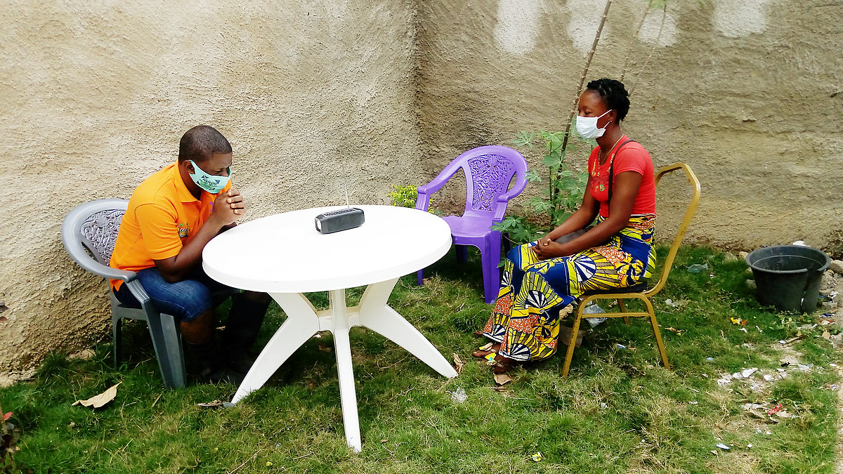 Photo: Two people sit on chairs outside at a round table.