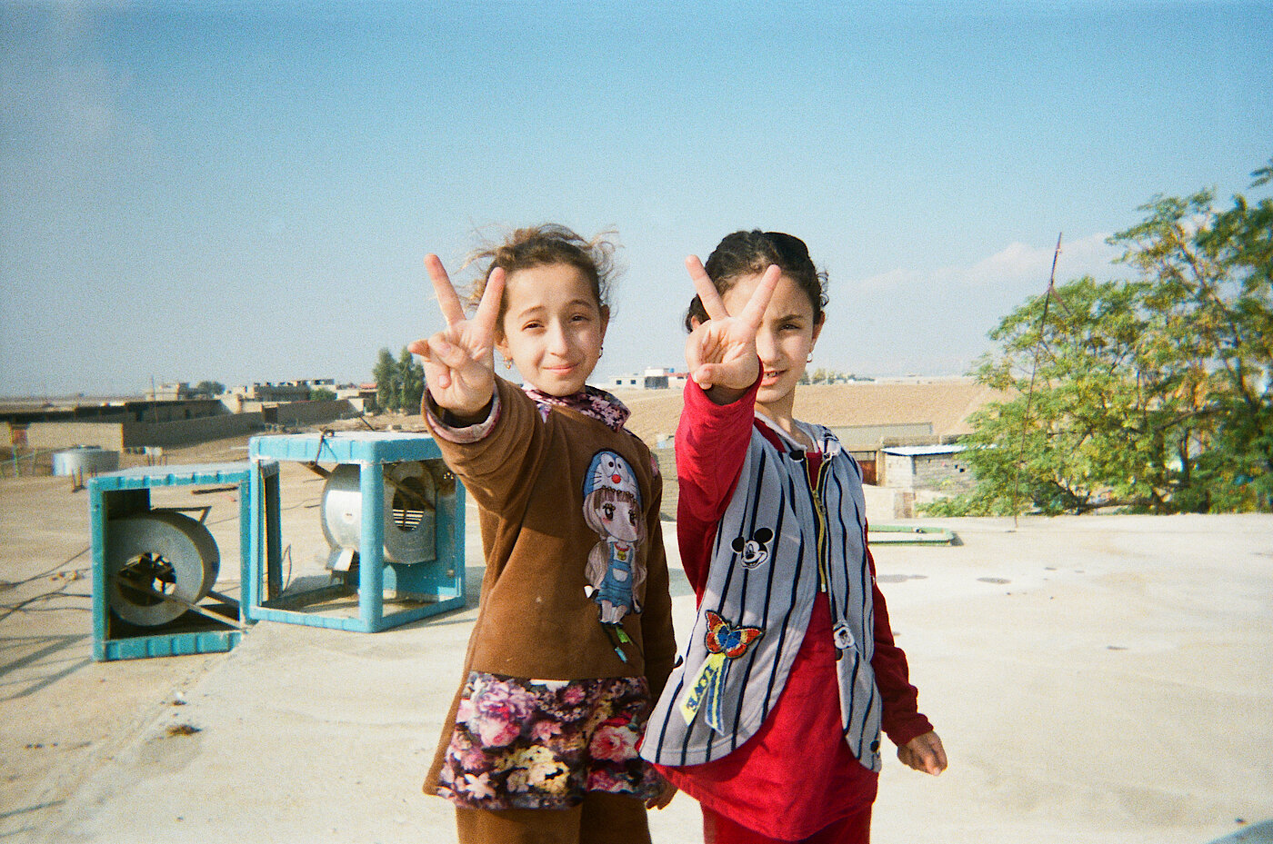 Photo: Two girls making the peace or victory sign with their hands.