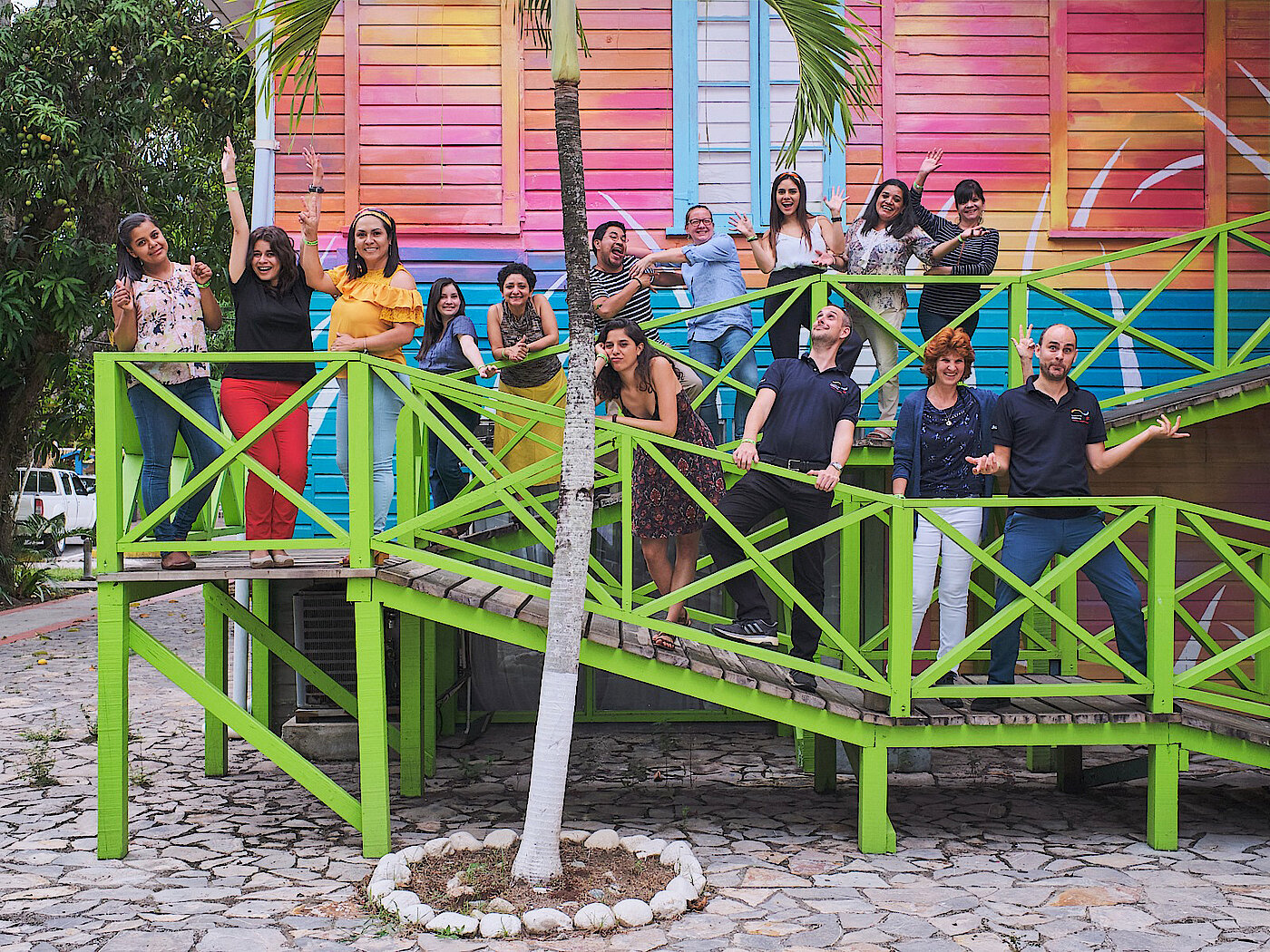 Photo: Several people standing on an access slope with green railings in front of a colourful building.