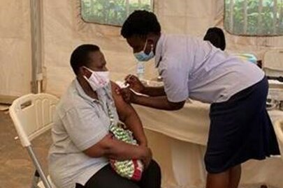 Foto: Eine Frau impft gerade eine Person. Beide tragen Mundschutz.