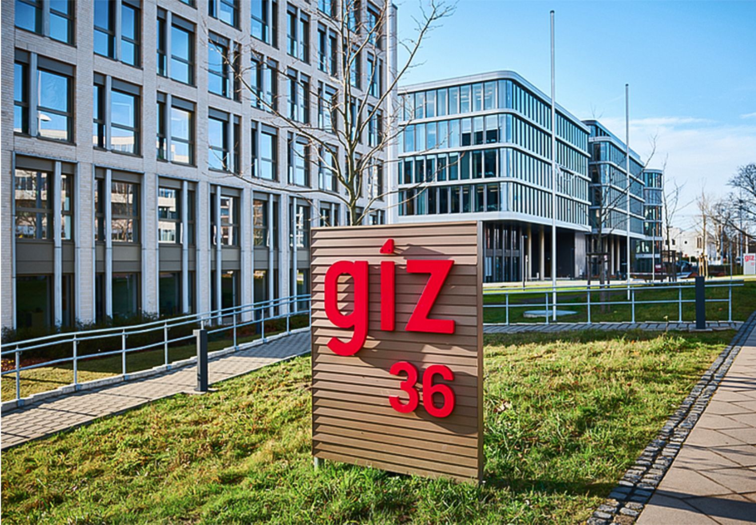 Photo: board with the inscription giz in front of several large, glassed-in buildings.