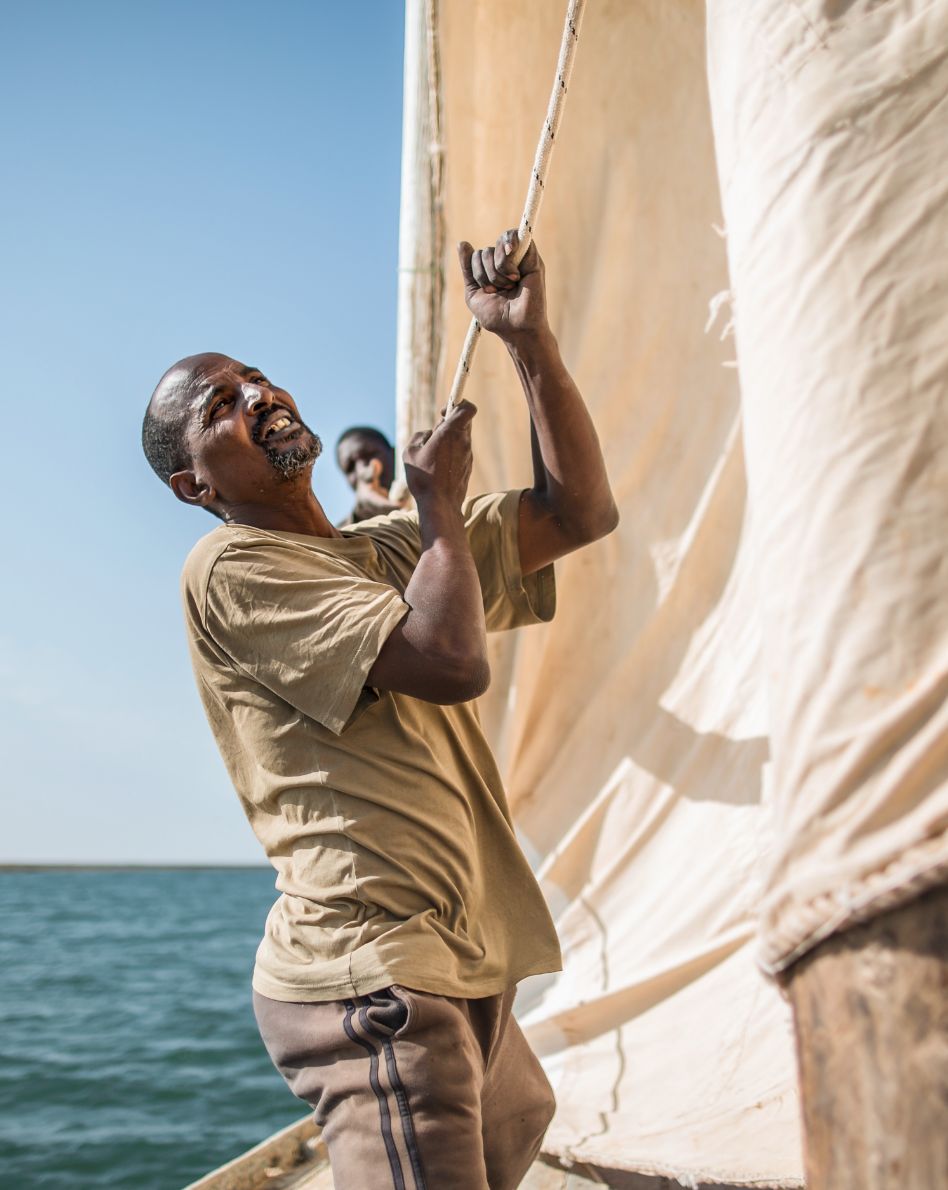 Photo: A man holds the rope of a sail.