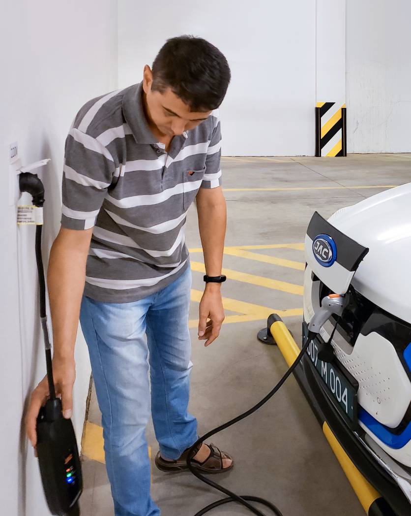Photo: A man looks at the charger to which an electric car is connected.