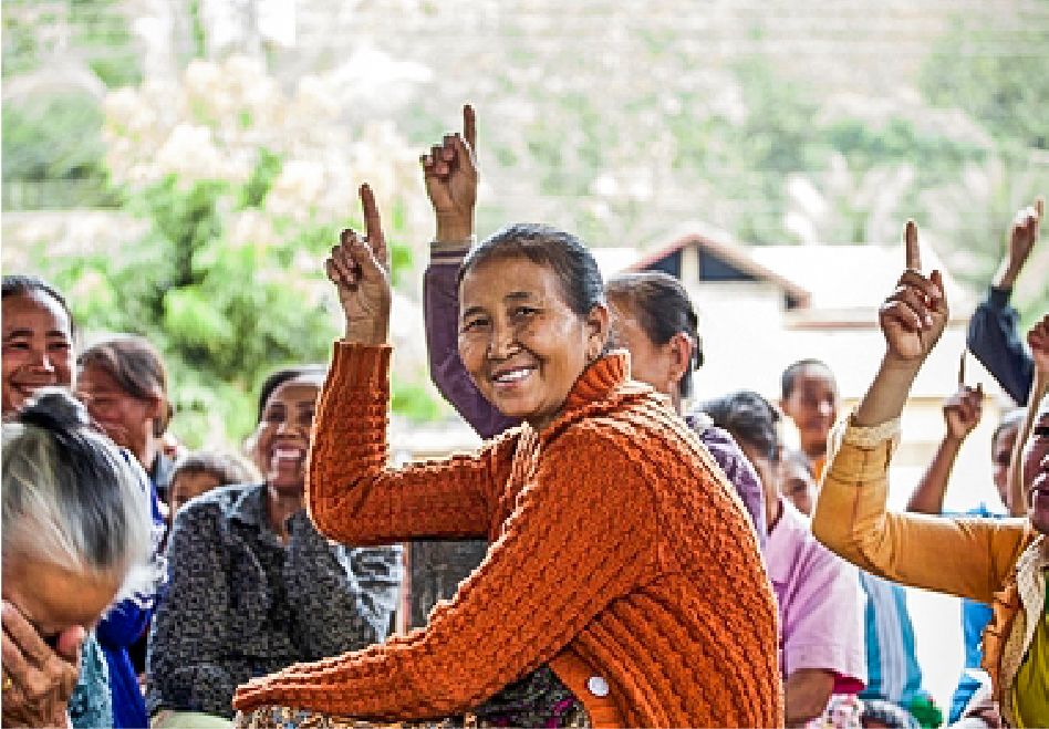 Photo: Several women, some of them raising their fingers in the air and laughing.