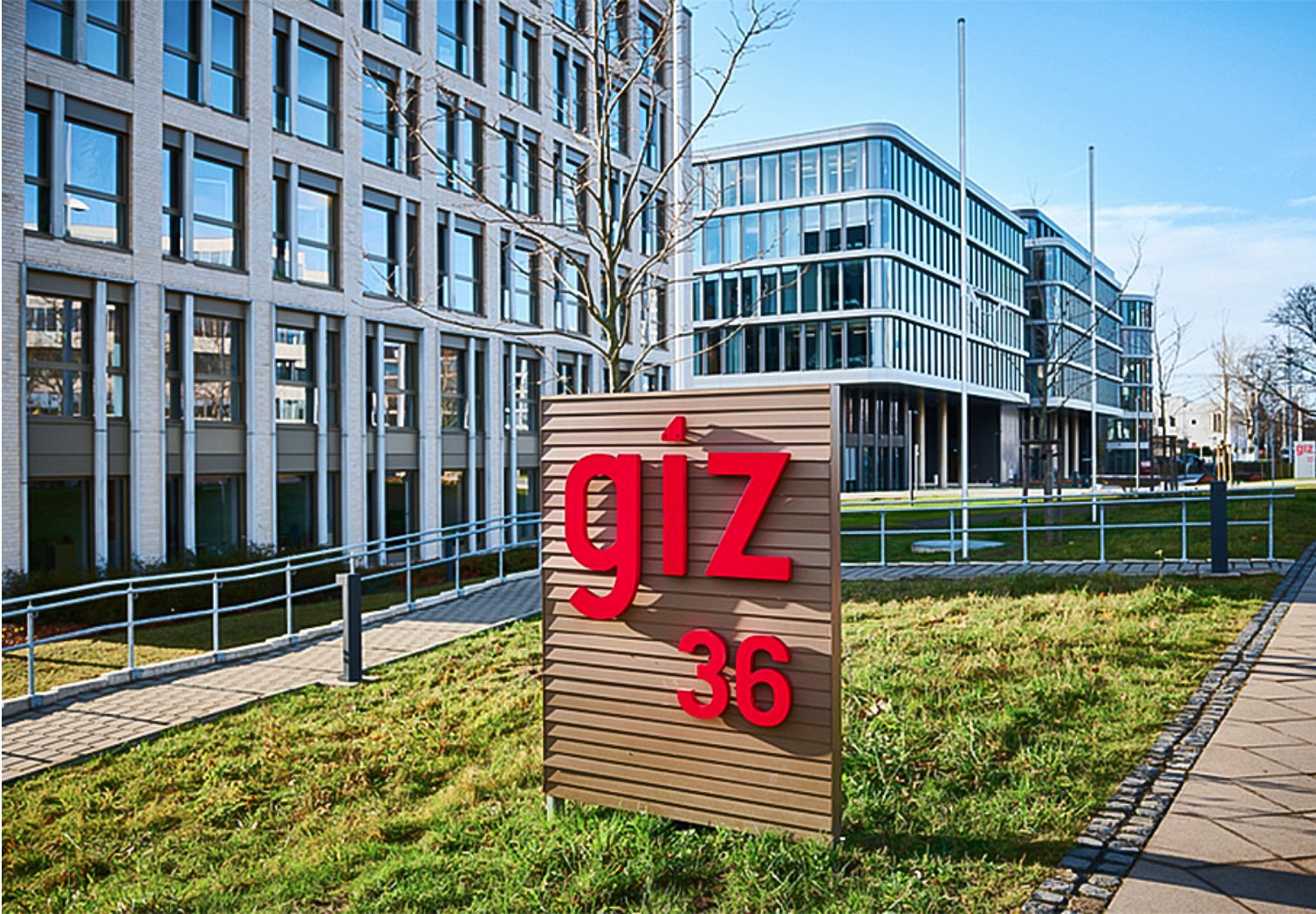 Photo: A sign bearing the GIZ logo in front of several modern buildings.