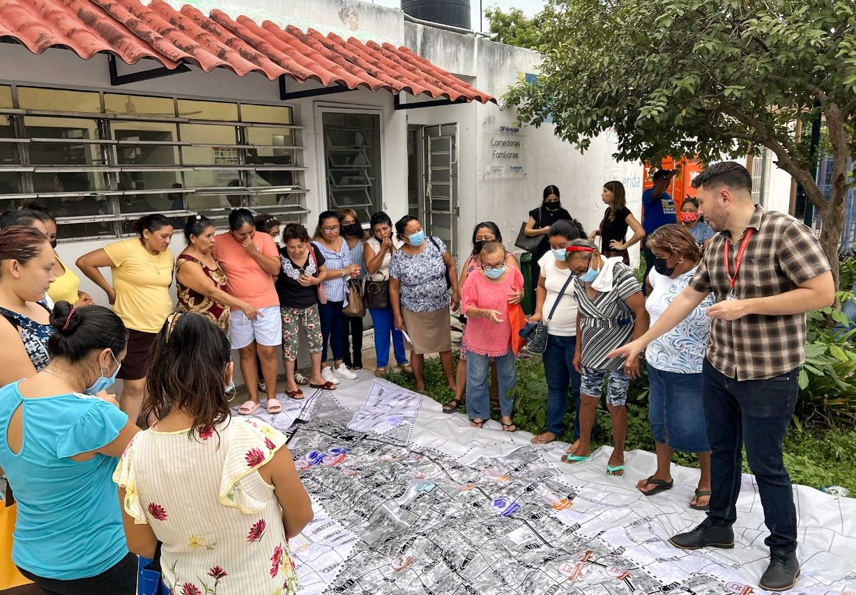 Photo: A group of people look together at a large city map lying on the ground.