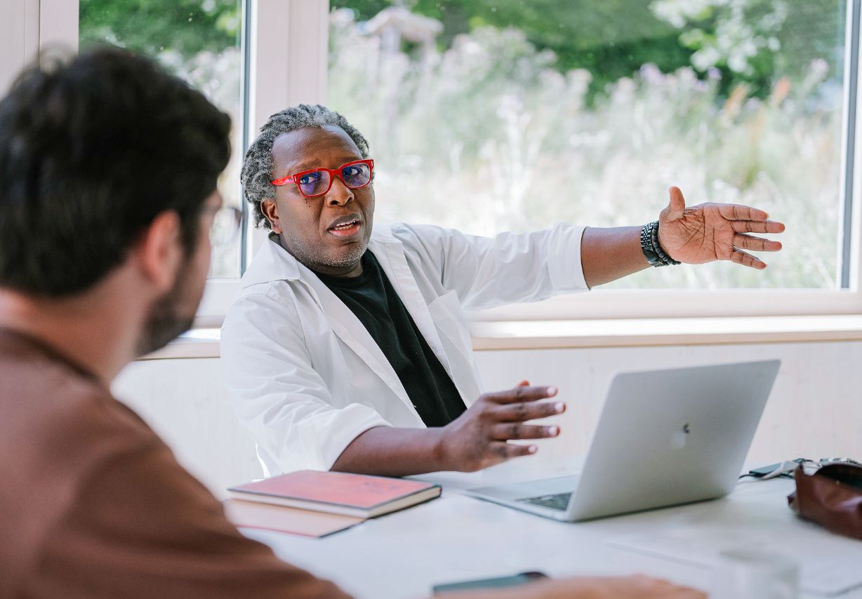 Photo: A man explains something. A laptop is on the table in front of him.