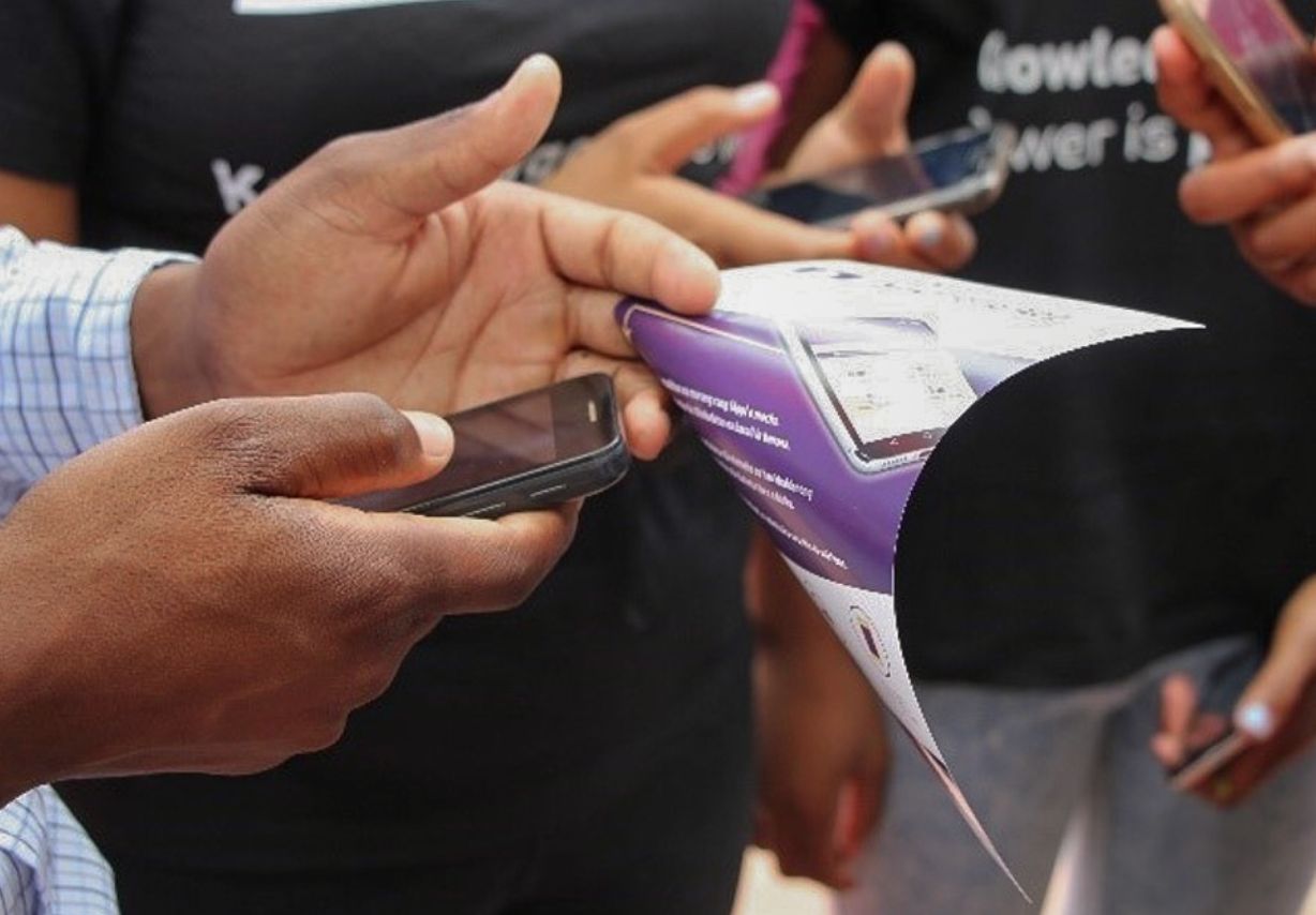 Photo: A pair of hands holding a smartphone and a flyer.