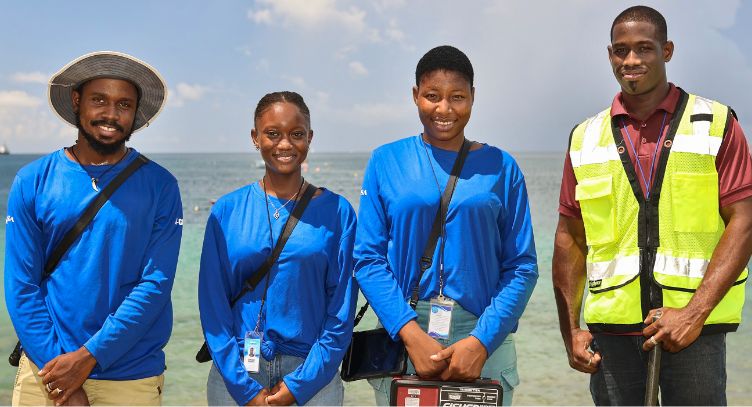 Photo: Four people in work clothes standing on a beach.