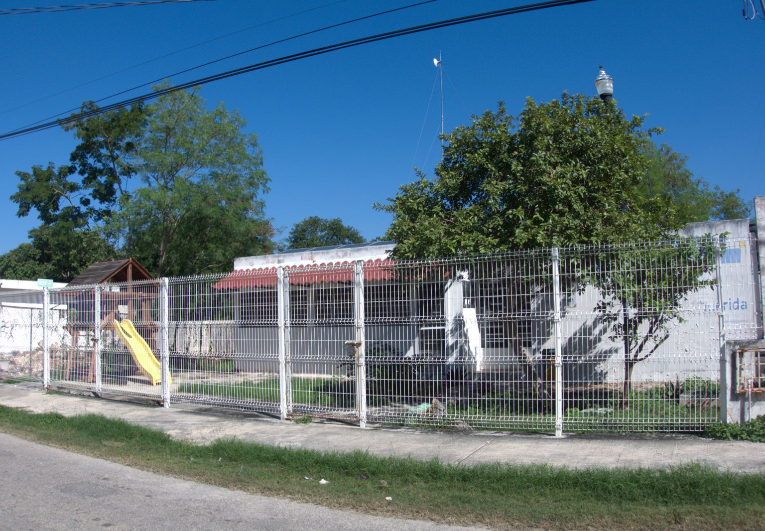 Photo: A slide, a tree, and a small building behind a fence.