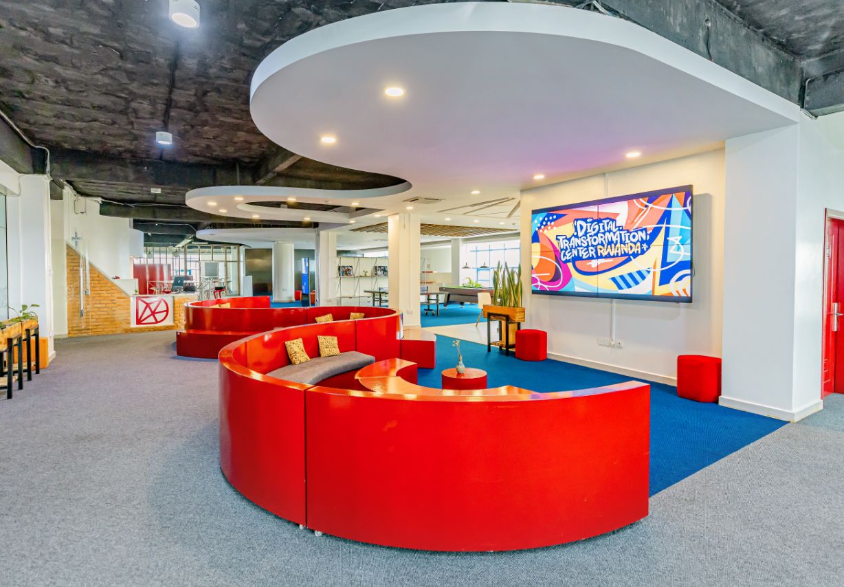 Photo: A futuristic-looking office space with curved red seating units and a large screen.