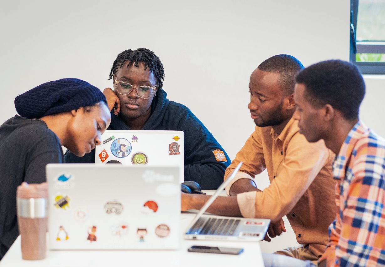 Photo: Four people with laptops sitting at a table.