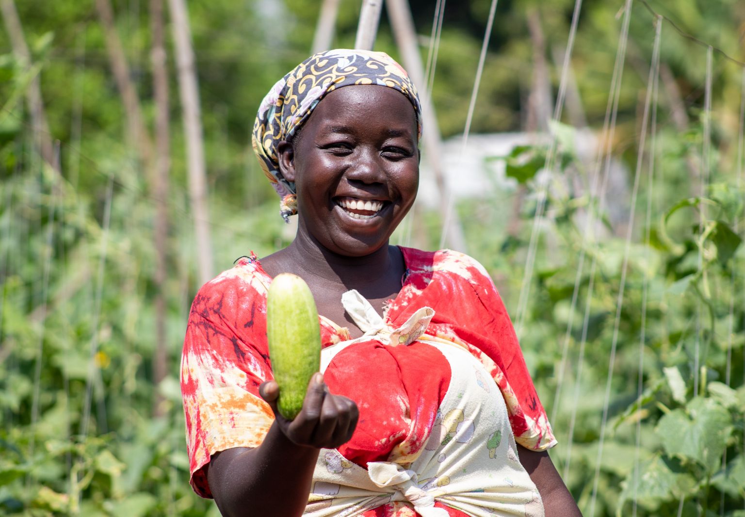 Photo: A woman holding a cucumber smiles at the camera.