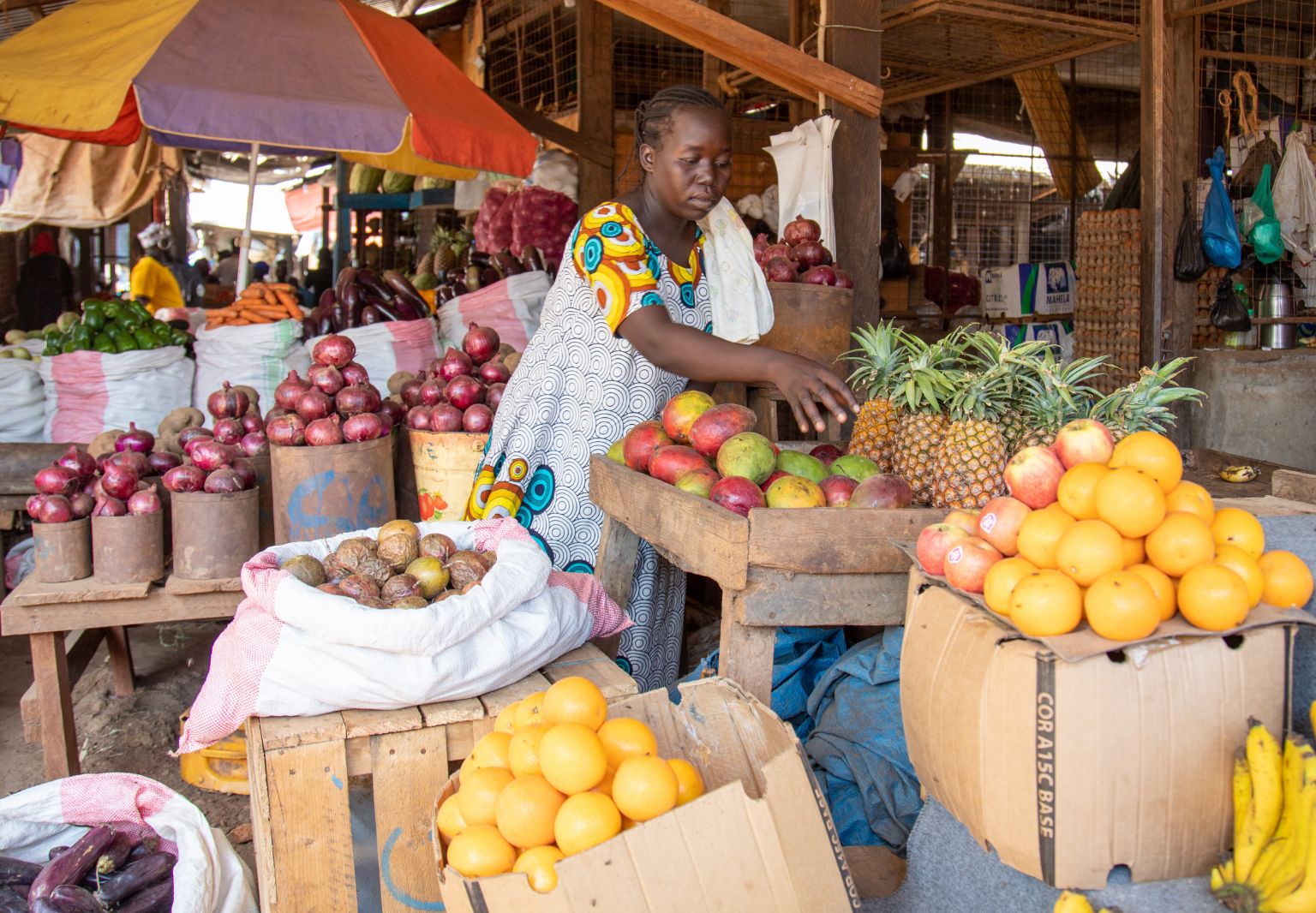 Photo: A woman selling tropical fruit at a market stall.