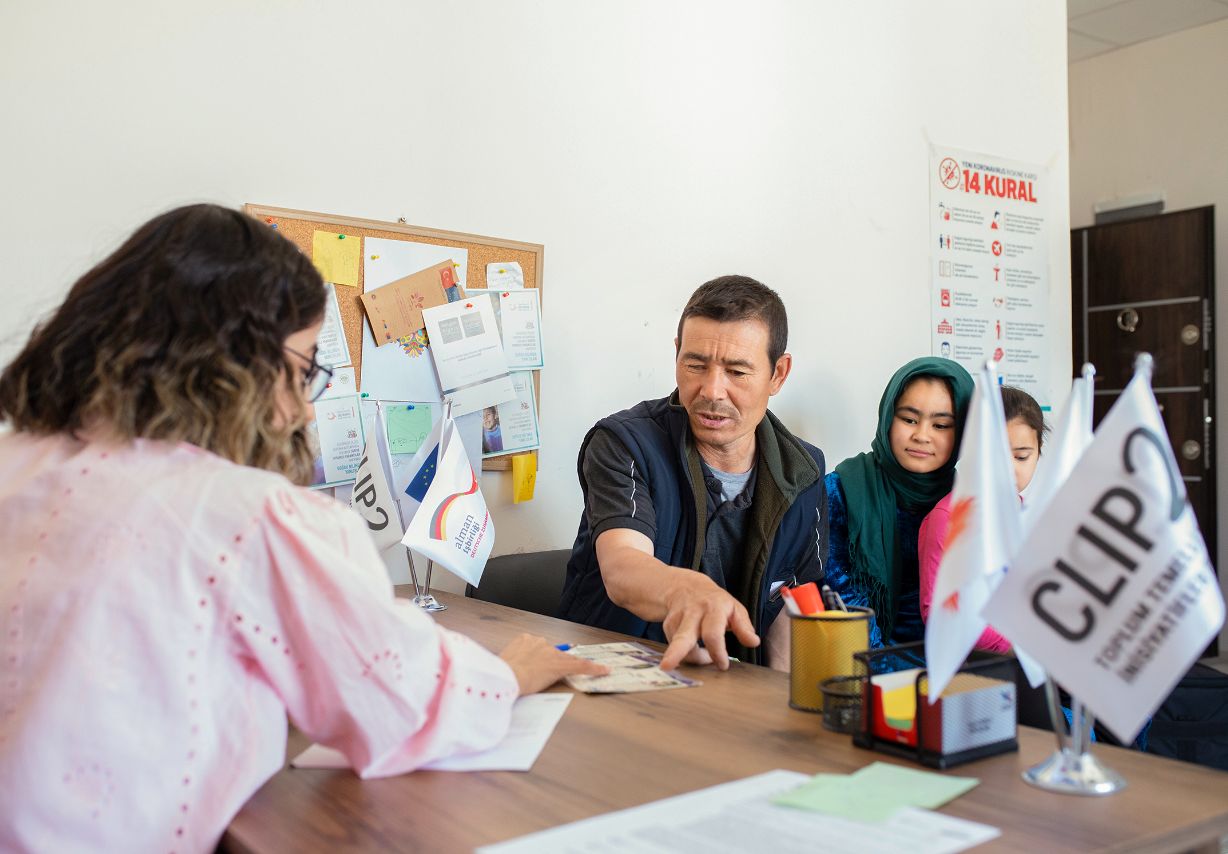 Photo: A woman and a family in discussion sit opposite each other at a desk. &copy; GIZ / 2022 Ali Saltan