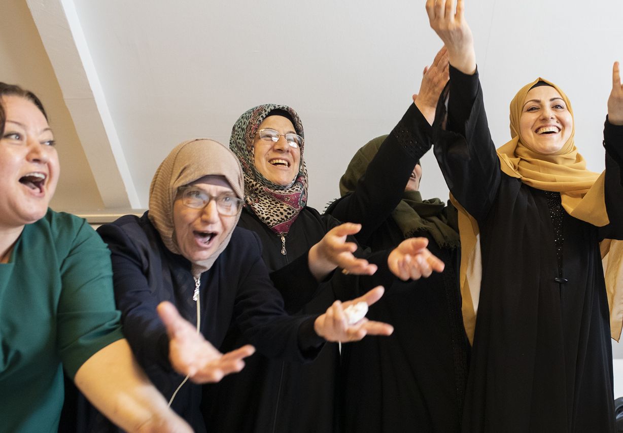 Photo: Several women wearing headscarves throw their hands in the air in jubilation. <br>&copy; GIZ / 2022 Ali Saltan