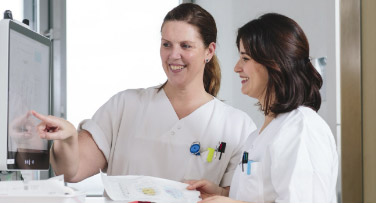 Photo: Two doctors looking at a computer monitor together.