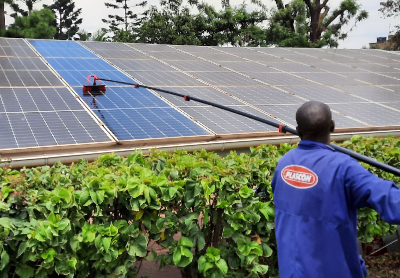 Photo: A man cleaning a photovoltaic system using an extendable pole.