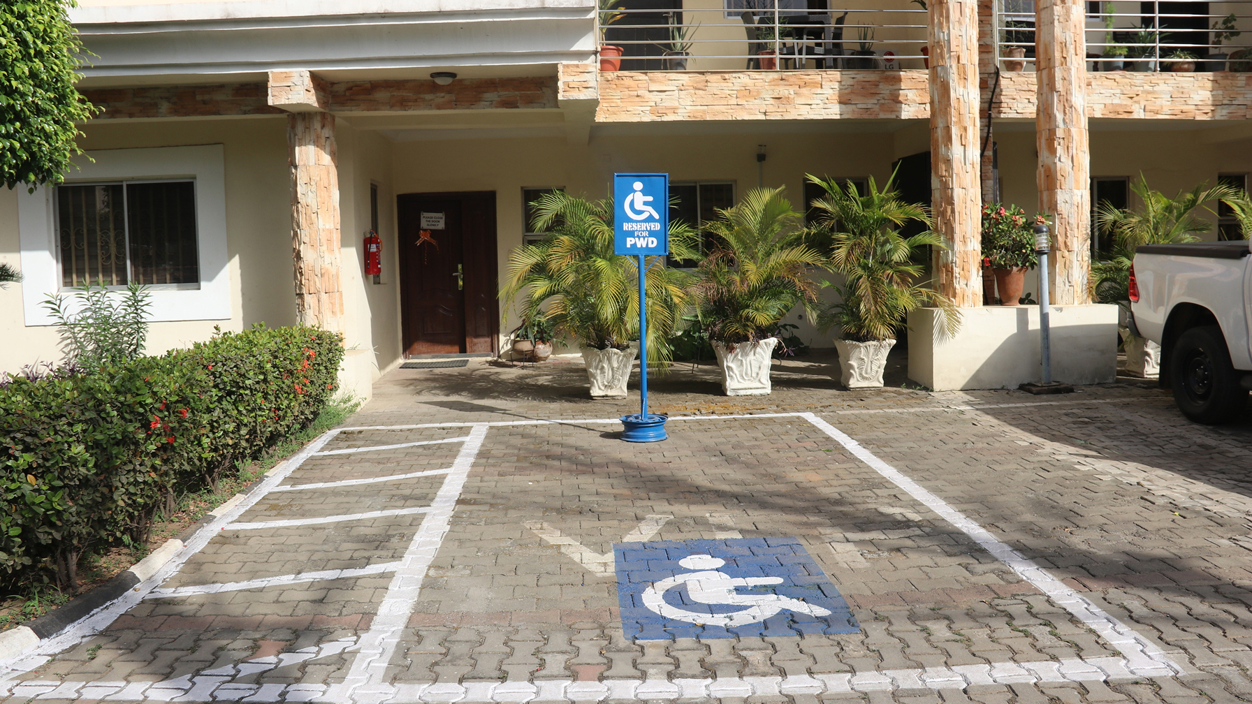 A designated parking space for people with disabilities in front of a building, indicated by markings on the ground and an information sign.