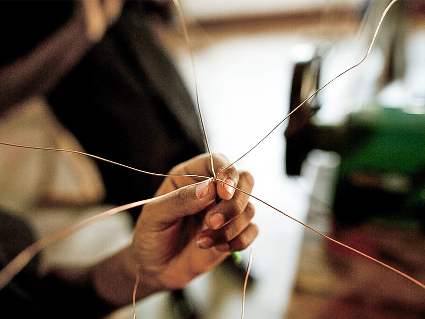 Close-up of a hand holding and twisting together several thin copper wires.